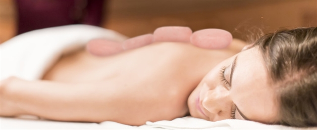 Woman laying face down with hot massage stones on her back Woman laying face down with hot massage stones on her back